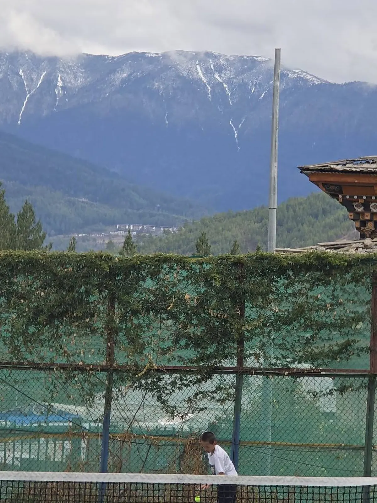 A player alone on court at Changlimithang beneath the snow line of the eastern Himalaya