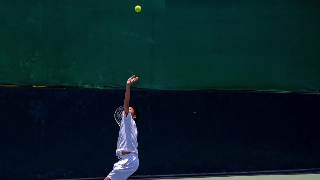 A junior player tossing the ball to serve at the National Tennis Centre, Changlimithang
