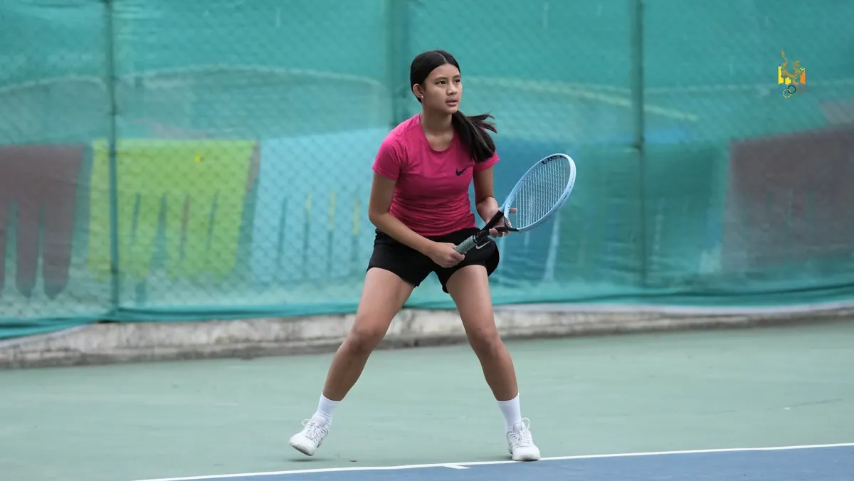 A junior girl waiting on the baseline in the ready position