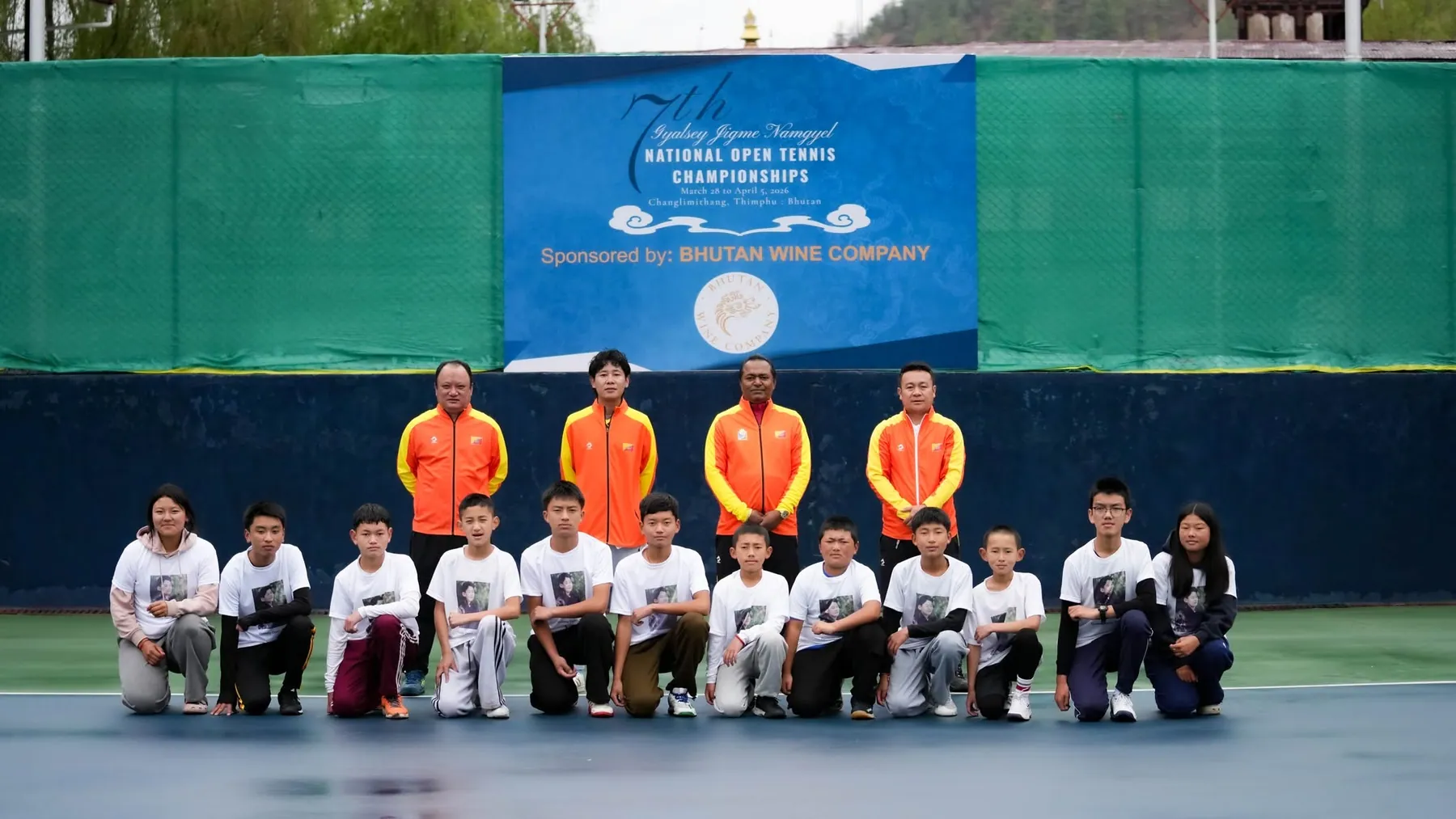 Juniors and coaches lined up on court beneath the National Open Tennis Championships banner